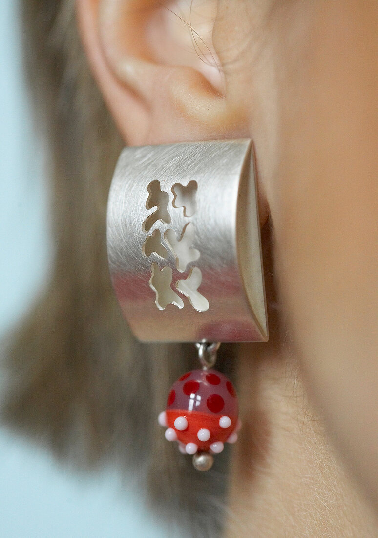 Close-up of silver earring with red and white spotted glass beads