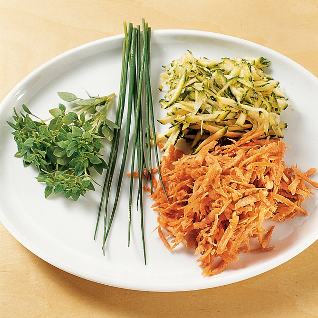 Carrots, grated zucchini, chives and herbs on plate