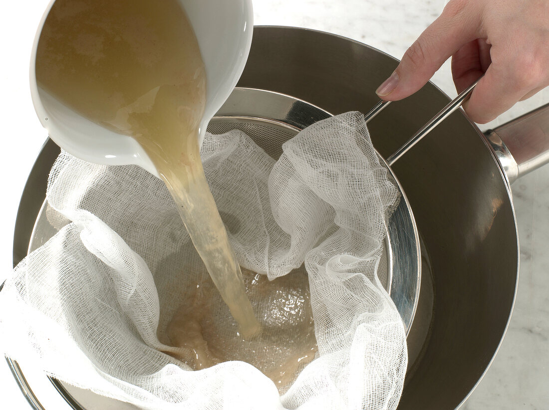 Sauce being poured in pan through cloth on strainer, step 3