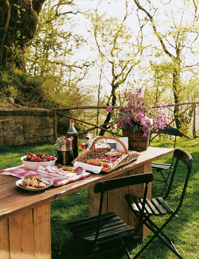 Laid table in garden with flowers in basket