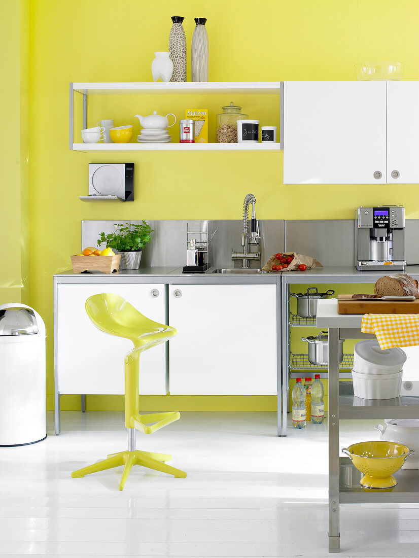 Kitchen with espresso machine and white stainless steel wall with yellow chair in front