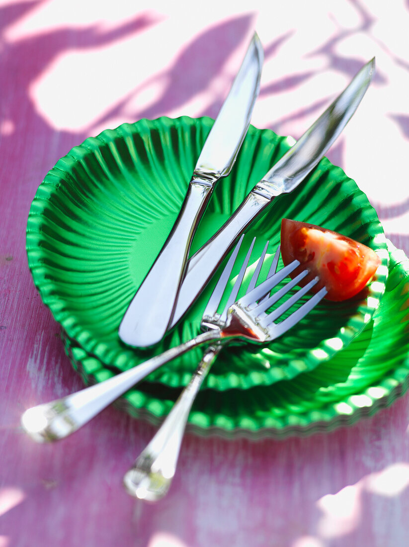 2 Steakmesser, 2 Gabel auf grünen Papptellern, Tomate