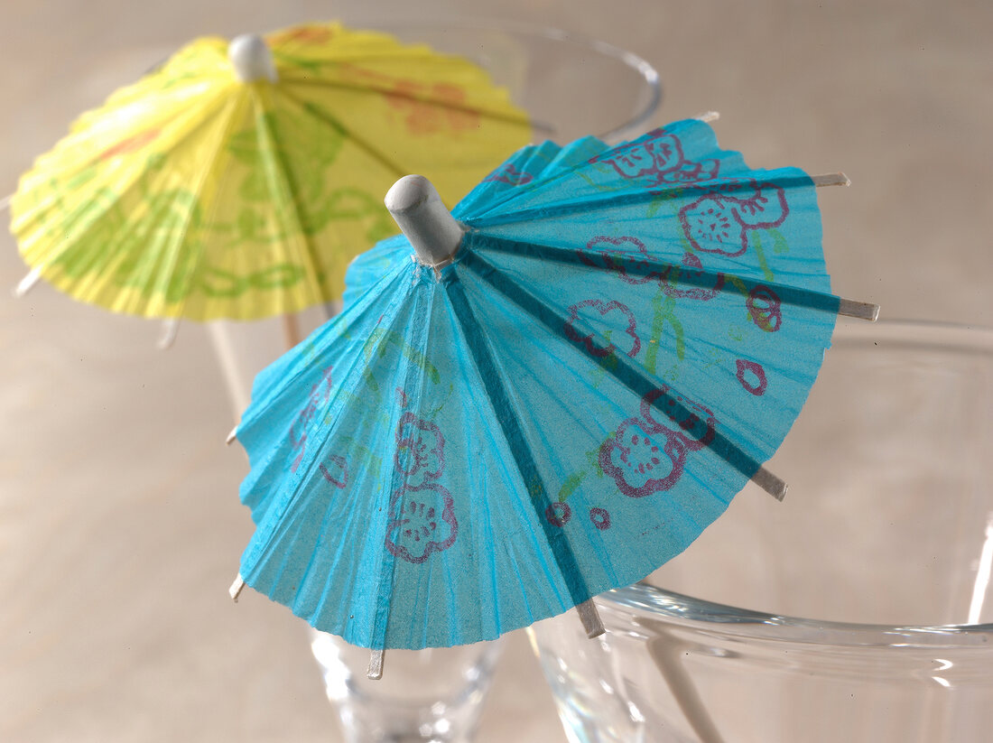 Close-up of yellow and blue paper umbrellas used for decorating cocktail glass