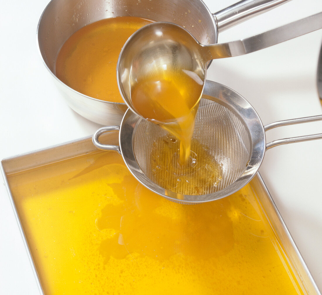 Butter being poured through strainer into baking tray to prepare lobster butter, step 6