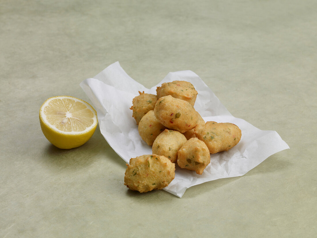 Asian fried fish balls with wild garlic dip on baking paper with sliced lemon