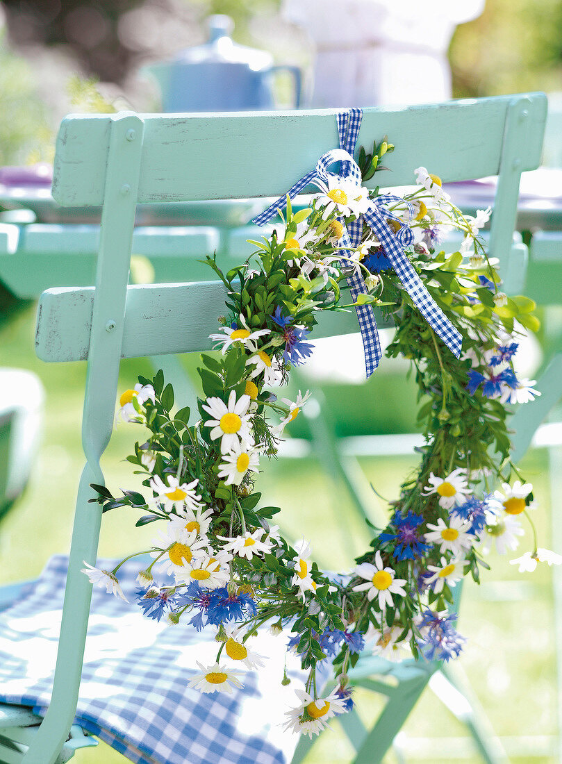 Close-up of wreath decorated of daisy flowers hanging on chair