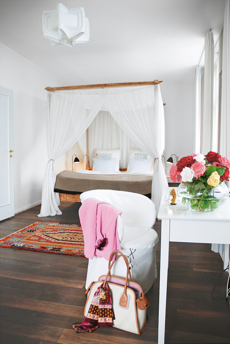 Room with four poster bed, table, chair and flower vase in Hotel Skovshoved, Denmark