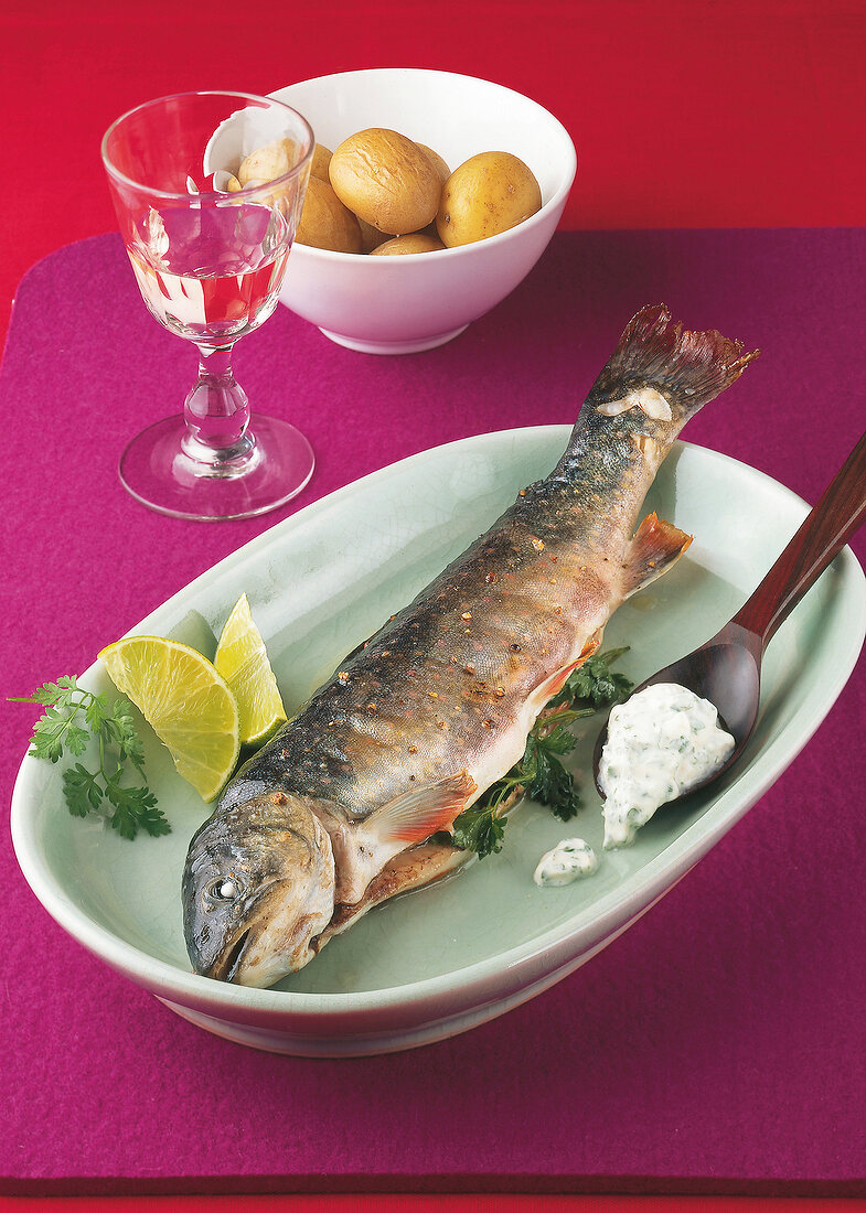 Salvelinus with chervil cream in serving dish and boiled potatoes in bowl