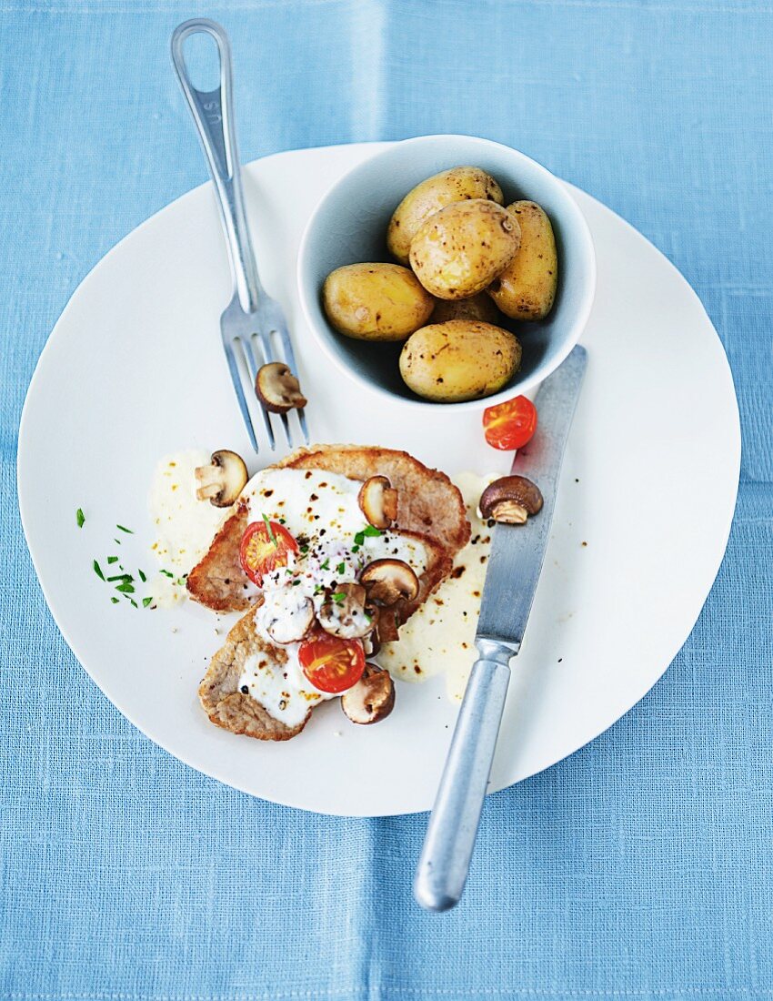 Überbackenes Schweinefleisch mit Champignons und Frühkartoffeln