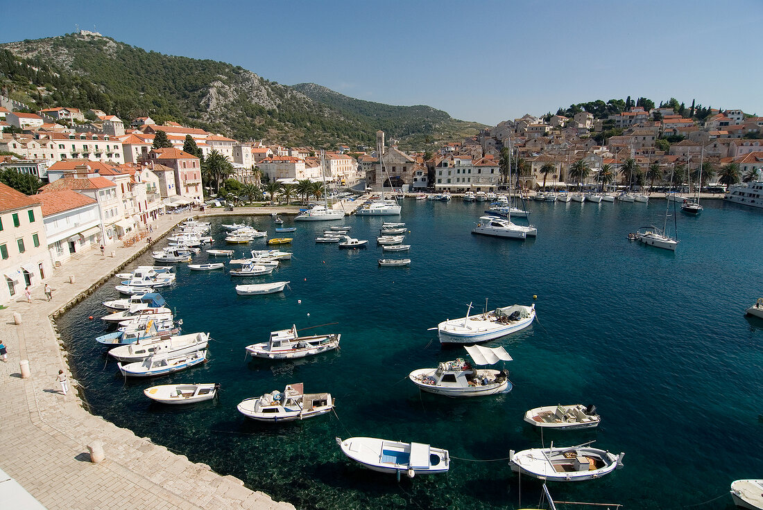 Dalmatien: Häuser, Boote im Hafen- becken, blauer Himmel