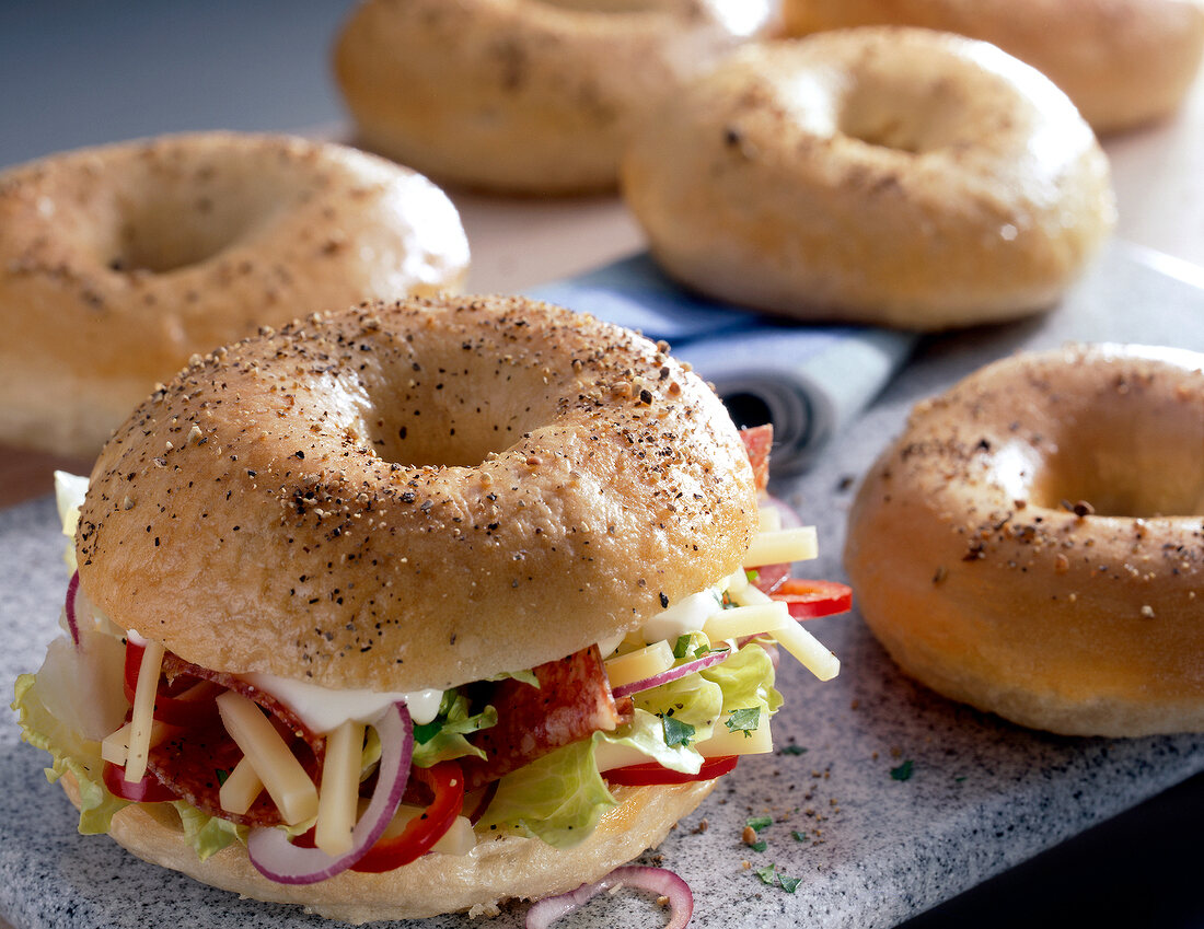 Close-up of bagel with lettuce, salami, cheese and onions