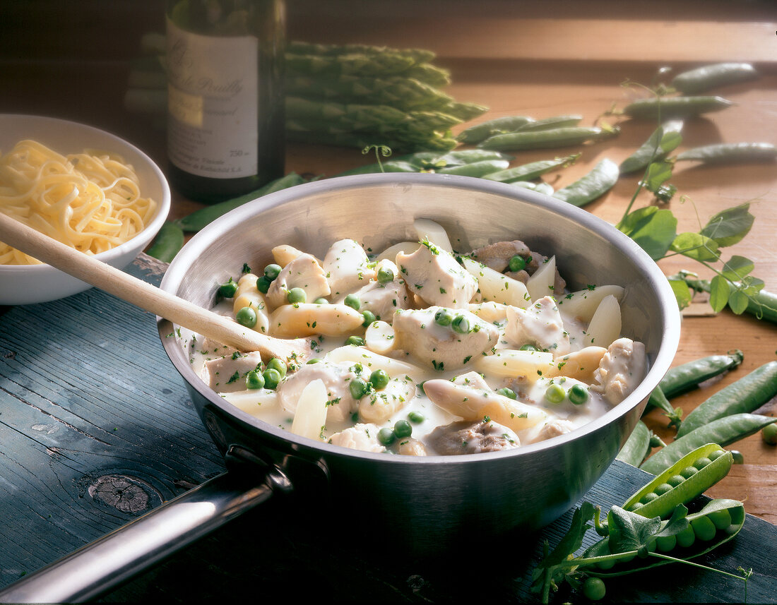 Pot of turkey with peas and asparagus in white sauce