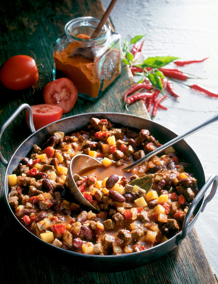 Ostrich stew with kidney beans and potatoes in pan with ladle