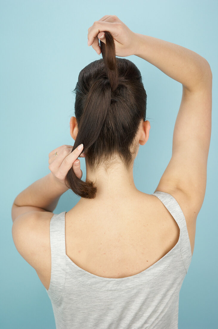 Rear view of woman tying the back section of her hair