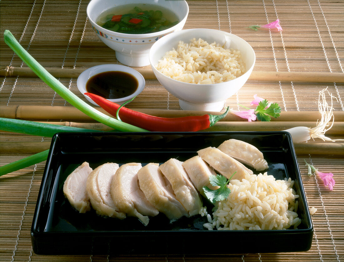 Slices of spring chicken with rice in black serving dish
