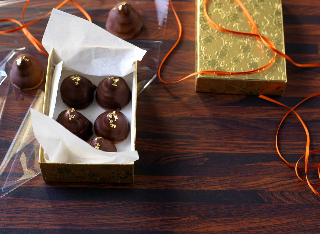 Chocolates in golden box with paper and orange ribbon