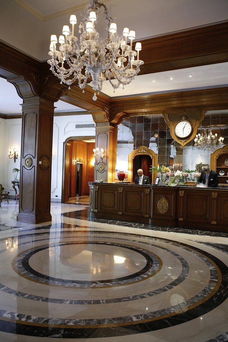 Receptionist standing at reception counter in hotel, Italy