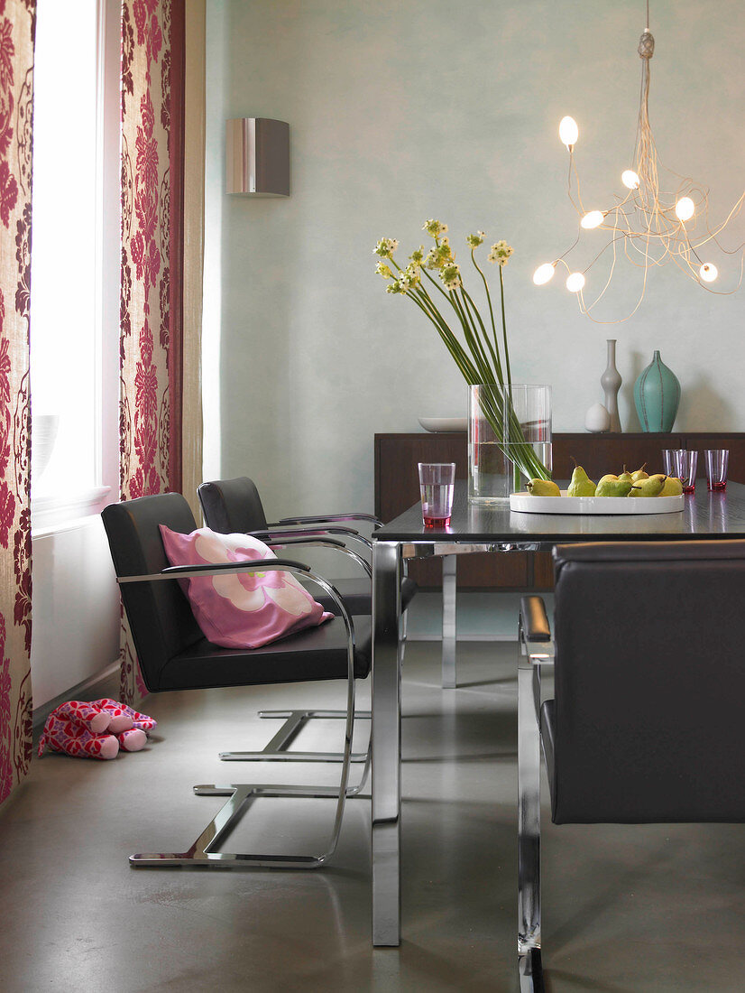 Brown leather chairs, dining table, sideboard, pink curtains and chandelier