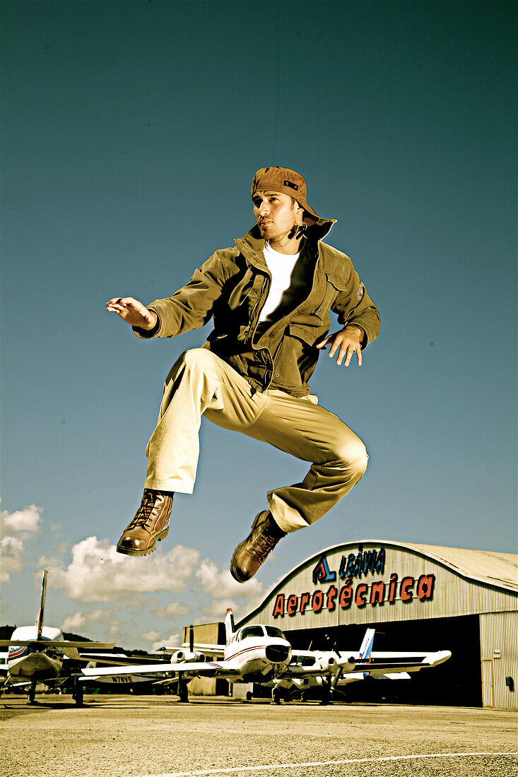 Man jumping in air with arms outstretched, smiling