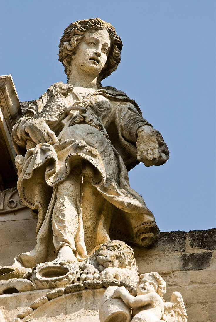 Low angle view of Angle's stone sculpture on a building roof in Lecce, Italy