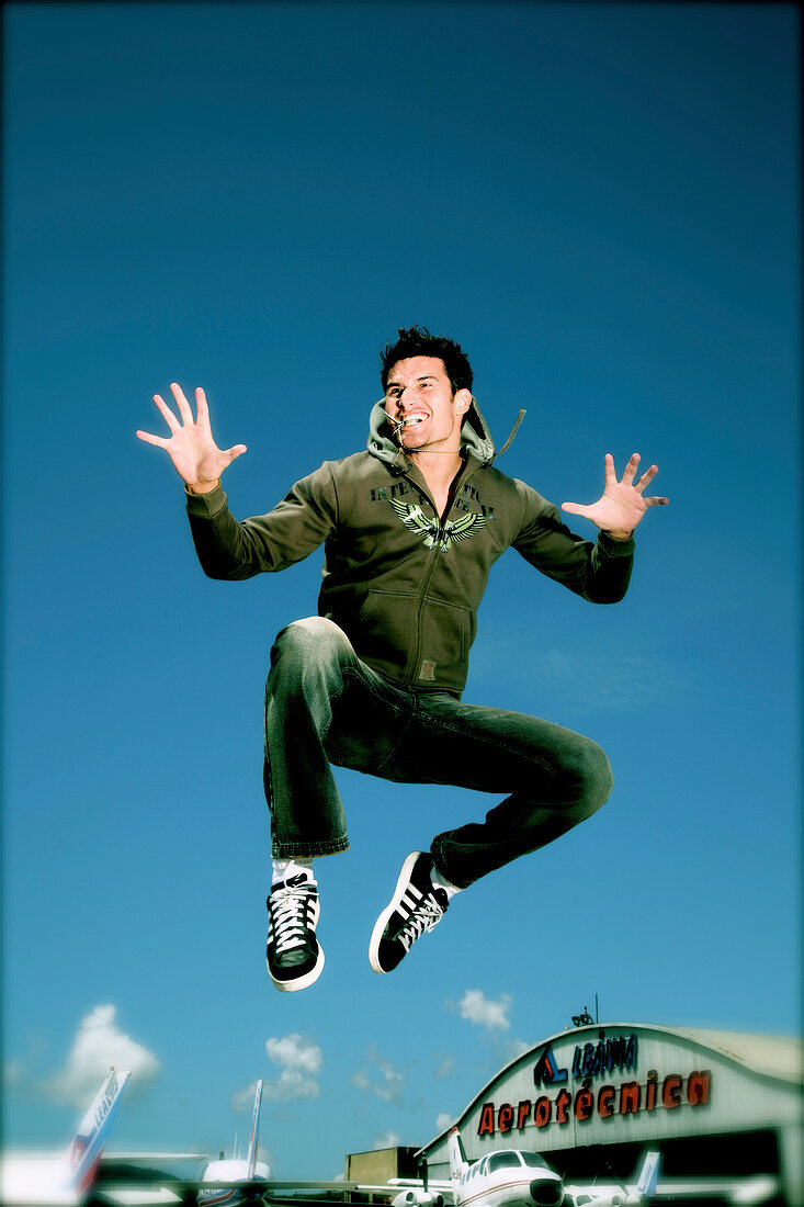Man jumping in air with arms outstretched, smiling