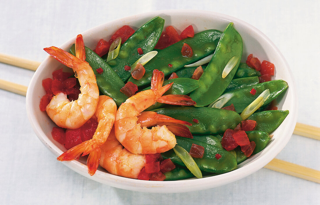 King prawns with sugar snap peas and tomatoes on plate