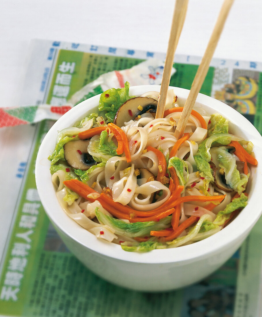Bowl of vegetables with rice noodles and chopsticks