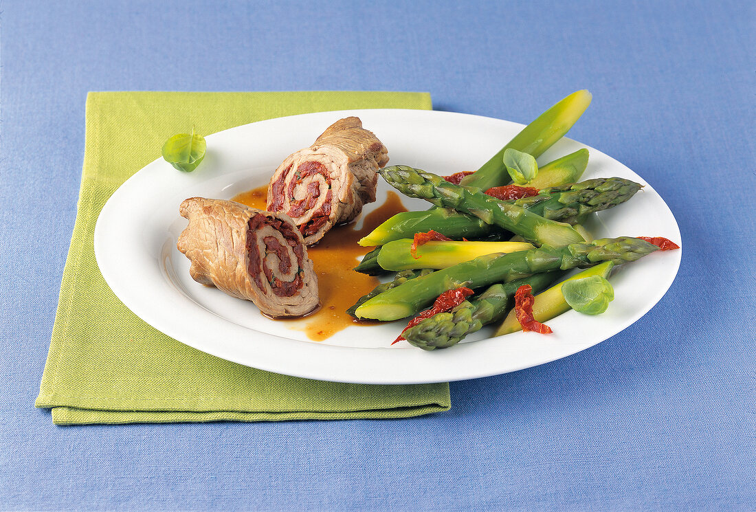 Pork roulade with green asparagus on plate