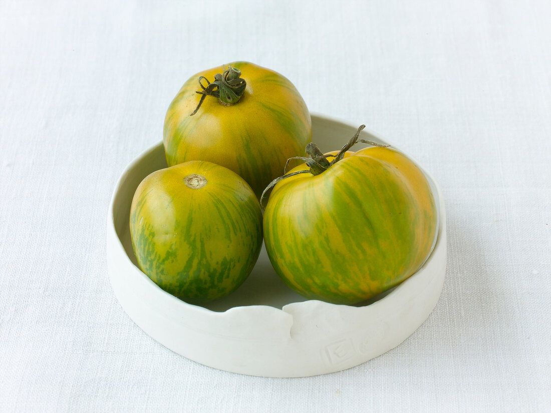 Three green zebra tomatoes on plate