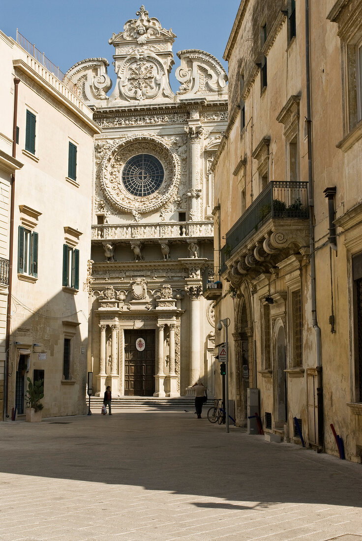 weiße Barock-Kirche, rundes Fenster, Wohnhäuser an den Seiten in Lecce