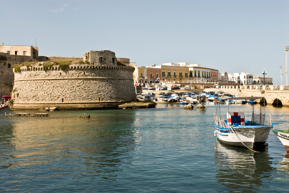 View of boats, houses, bridge and harbour wall at port of Gallipoli, Italy