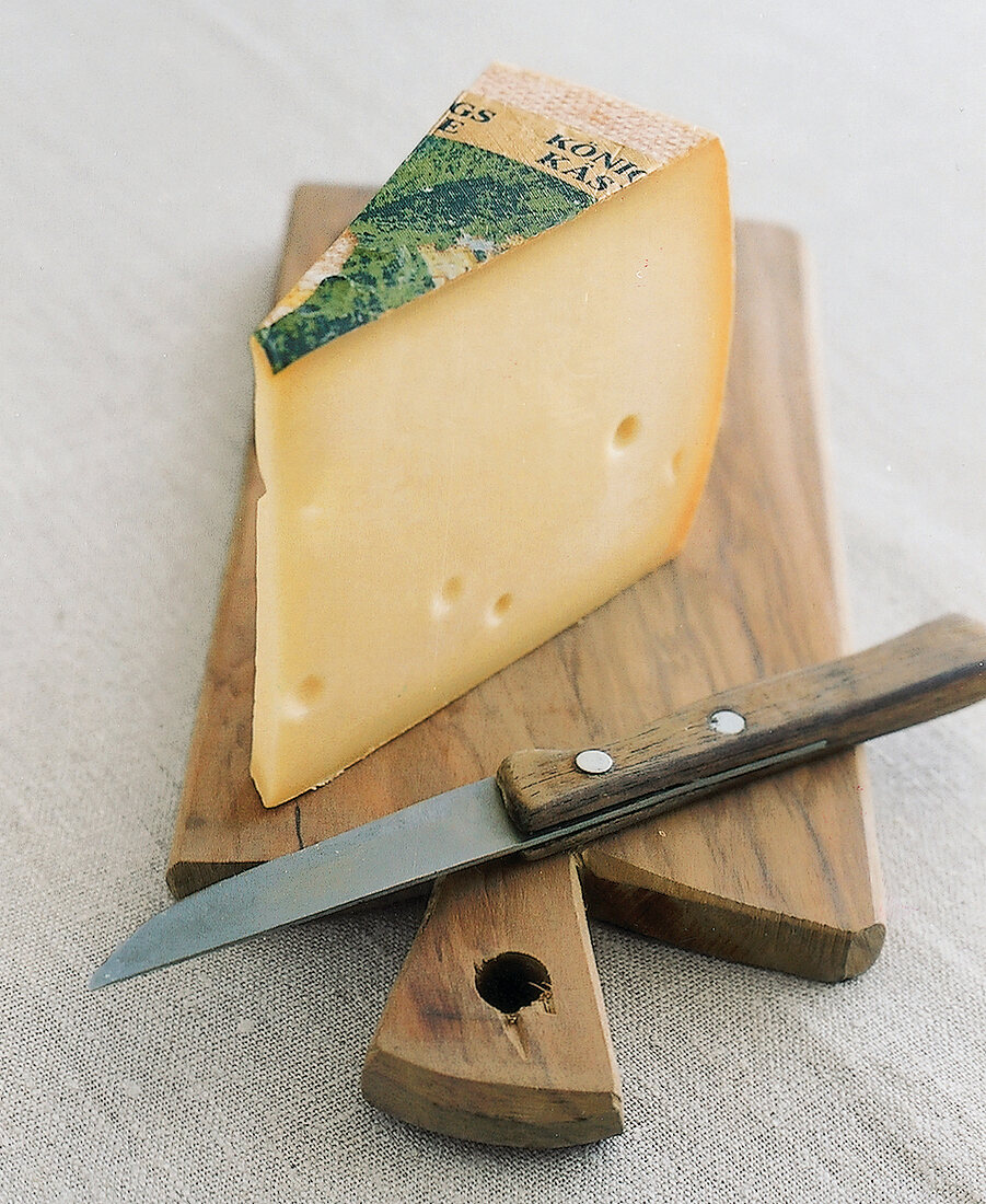 Raclette, 1 Stück Butterkäse auf einem Holzbrett mit einem Messer