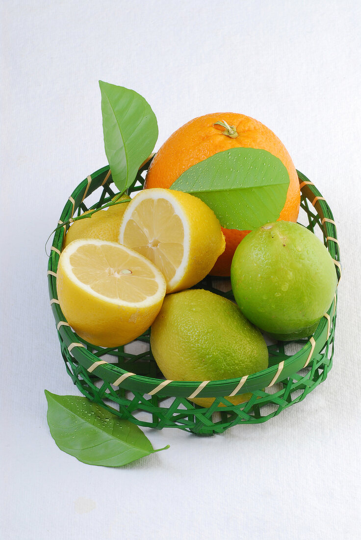 Close-up of orange and lemons in green cane basket
