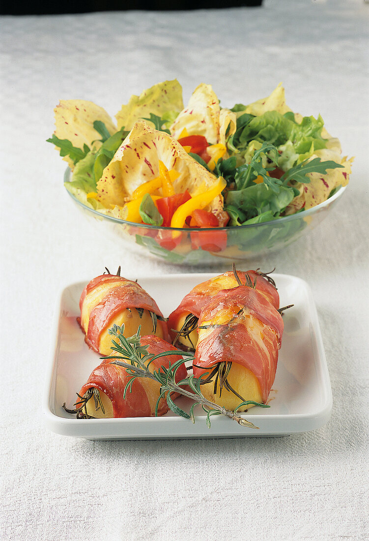 Ham with rosemary and potatoes and bowl of salad