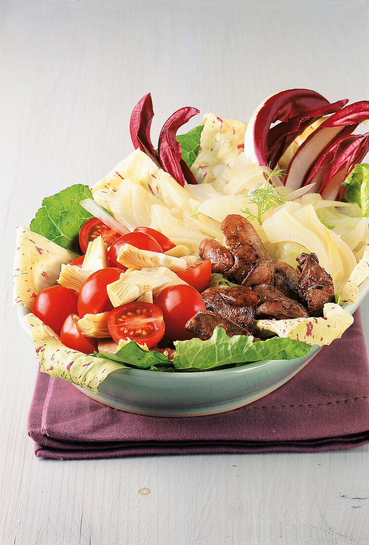 Close-up of salad with fried chicken liver and tomatoes in bowl