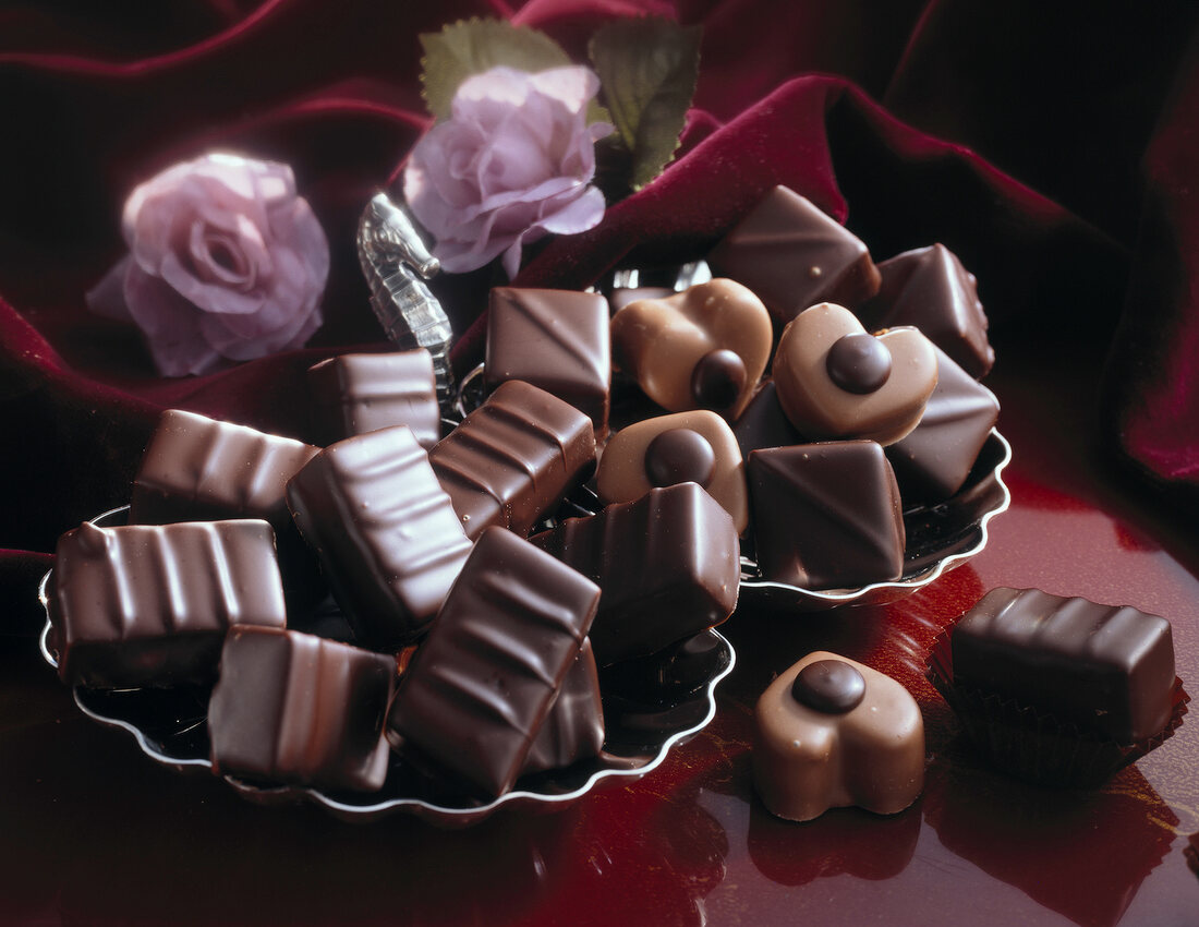 Close-up of various chocolates in bowls with roses