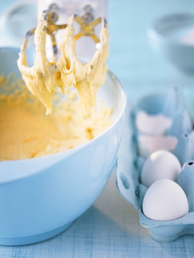 An electric whisk and a mixing bowl with cake mixture