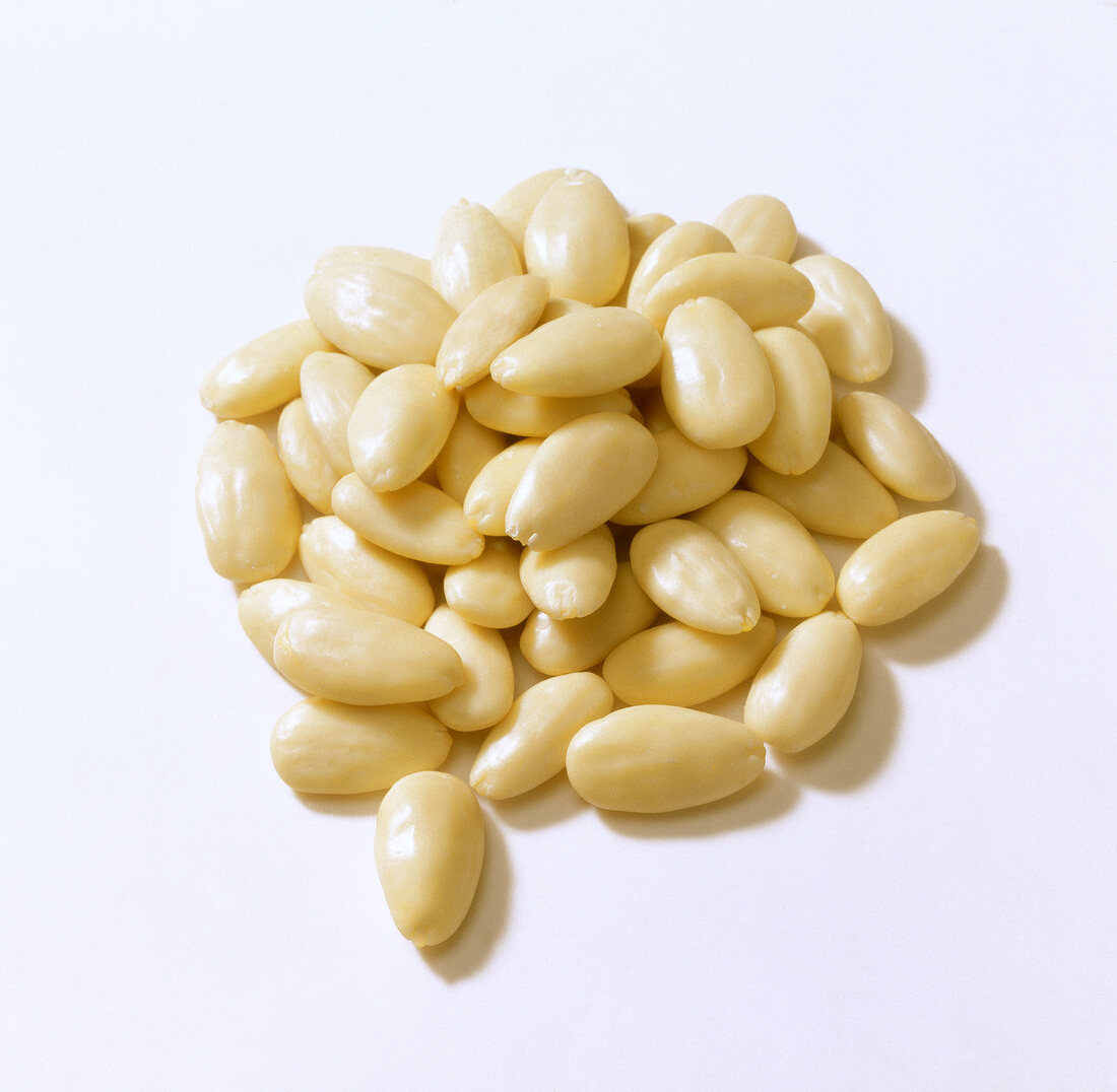 Close-up of peeled almonds on white background