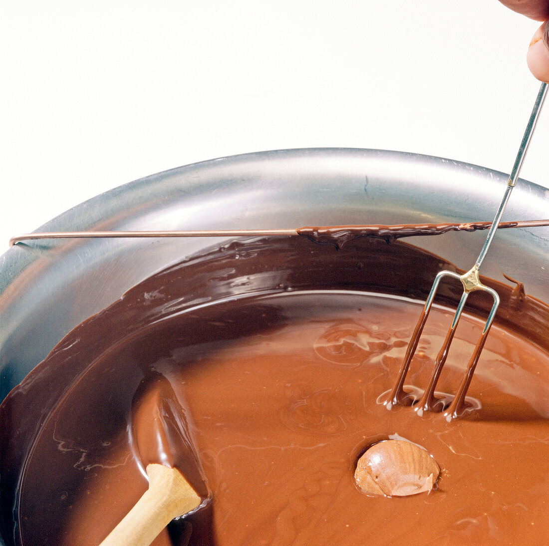 Close-up of ganache balls being dipped in melted chocolate, step 1