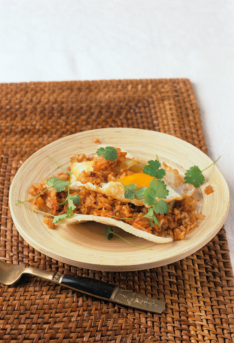 Rice with fried eggs garnished with coriander leaves on plate