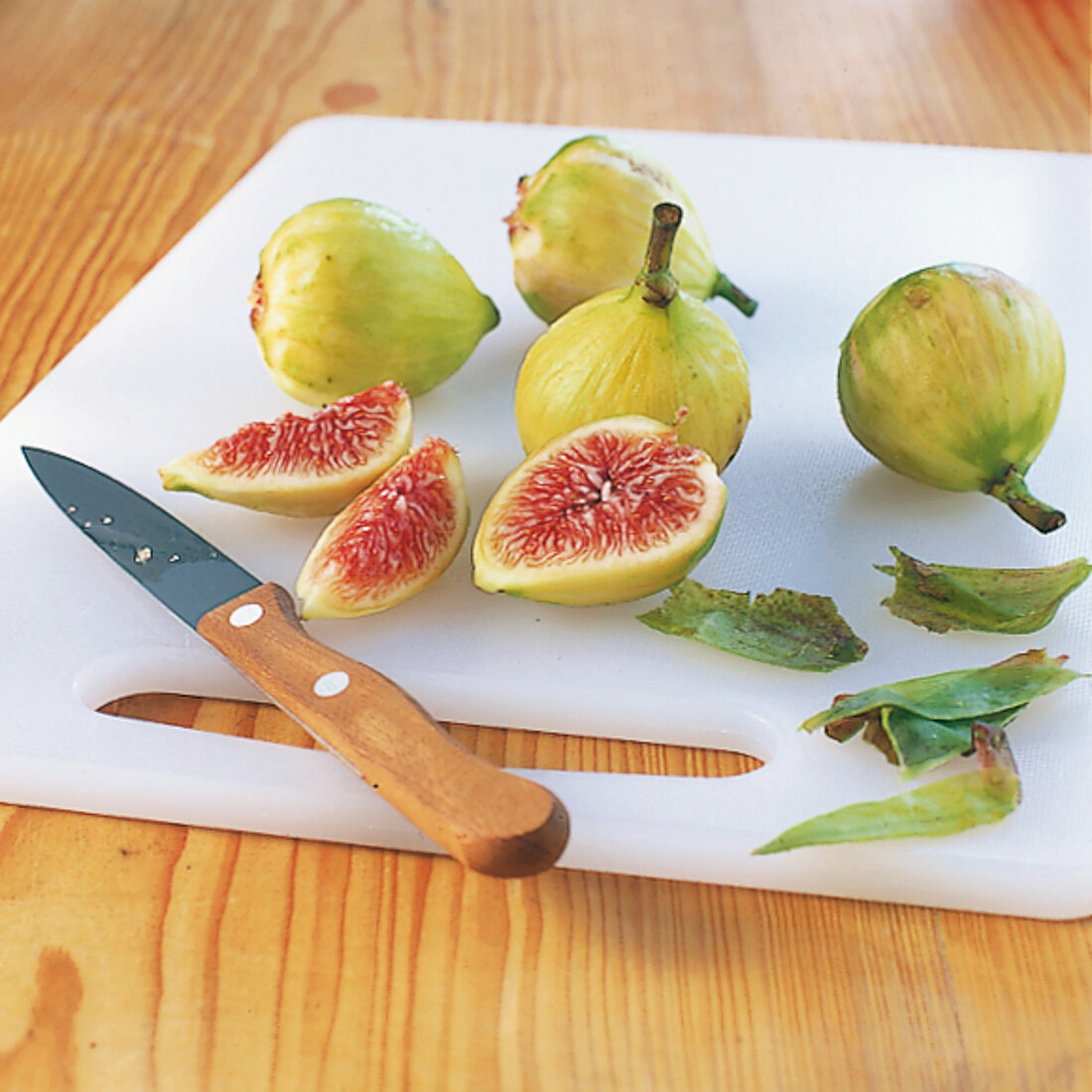 Close-up of figs being peeled and cut into quarter on cutting board