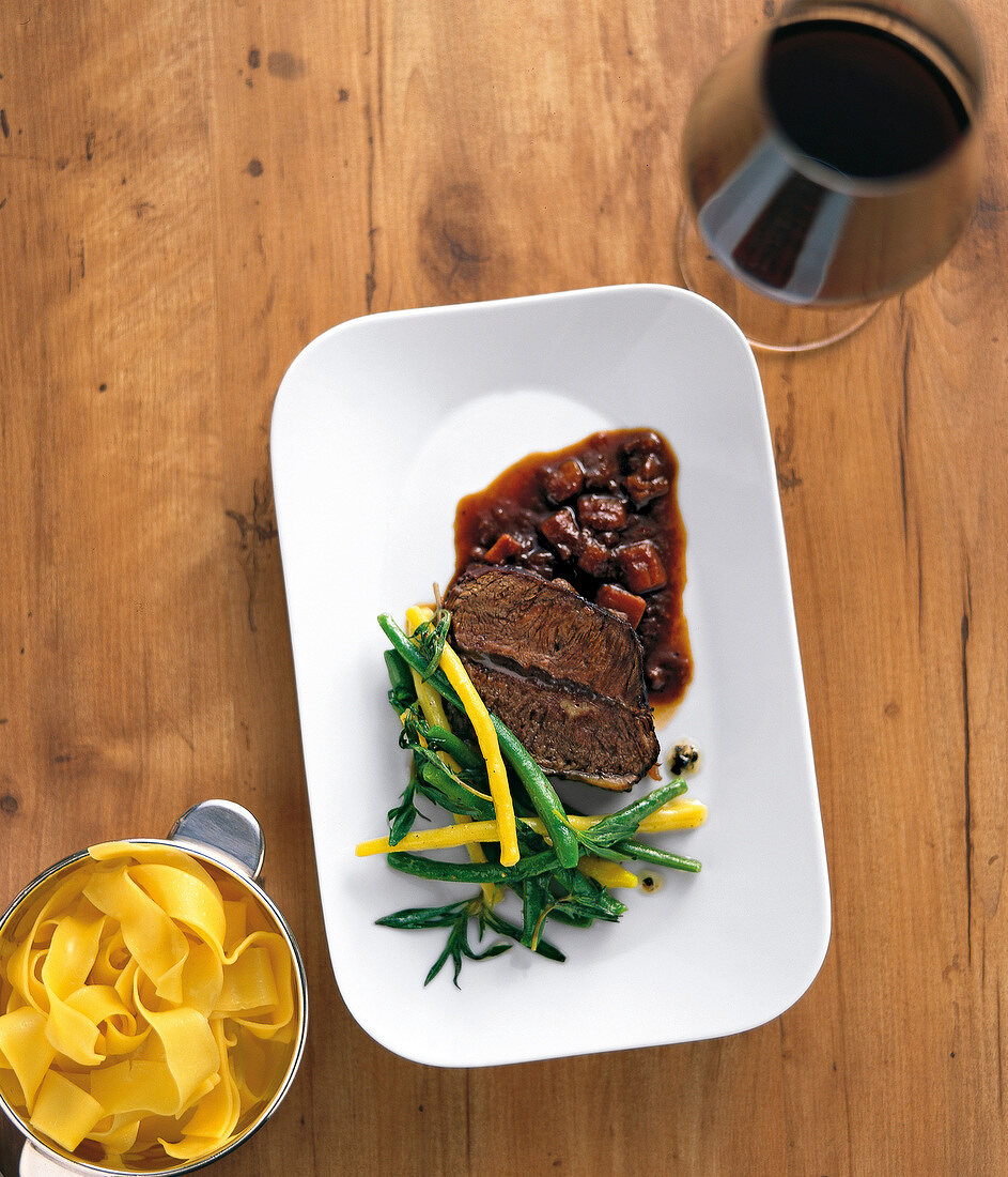 Beans, noodles and shoulder of beef braised in red wine in serving dish