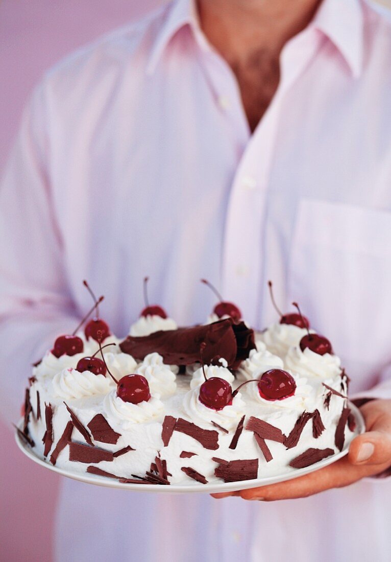 Mann hält Schwarzwälder Kirschtorte in den Händen