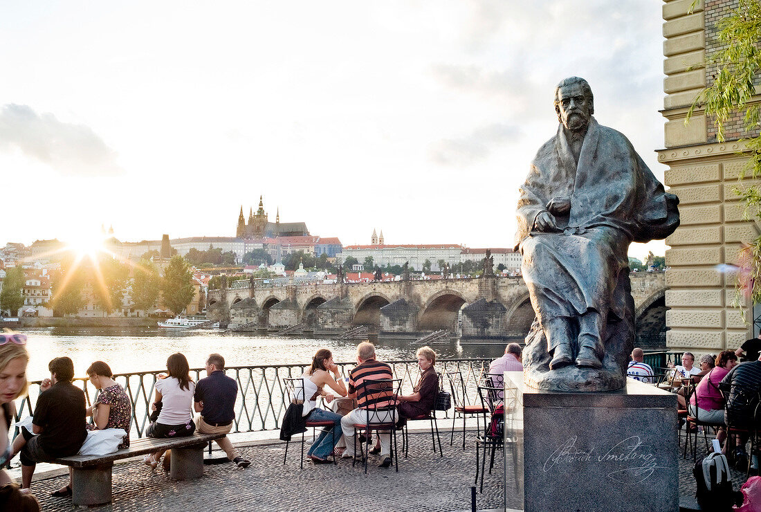 People sitting near Smetana Memorial at sunset, Prague