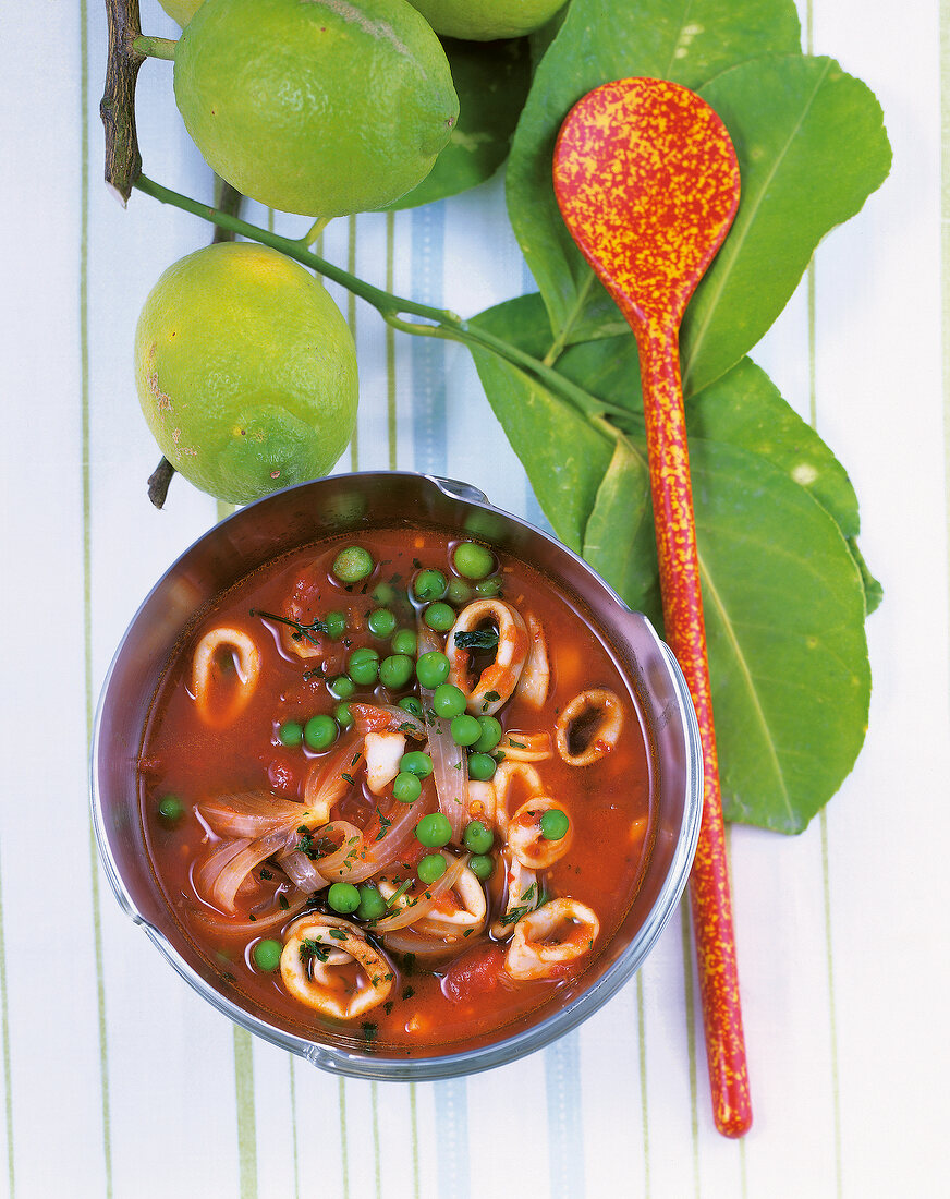 Kochen, Calamaritopf mit Tomaten und Erbsen, Limetten, Kochlöffel