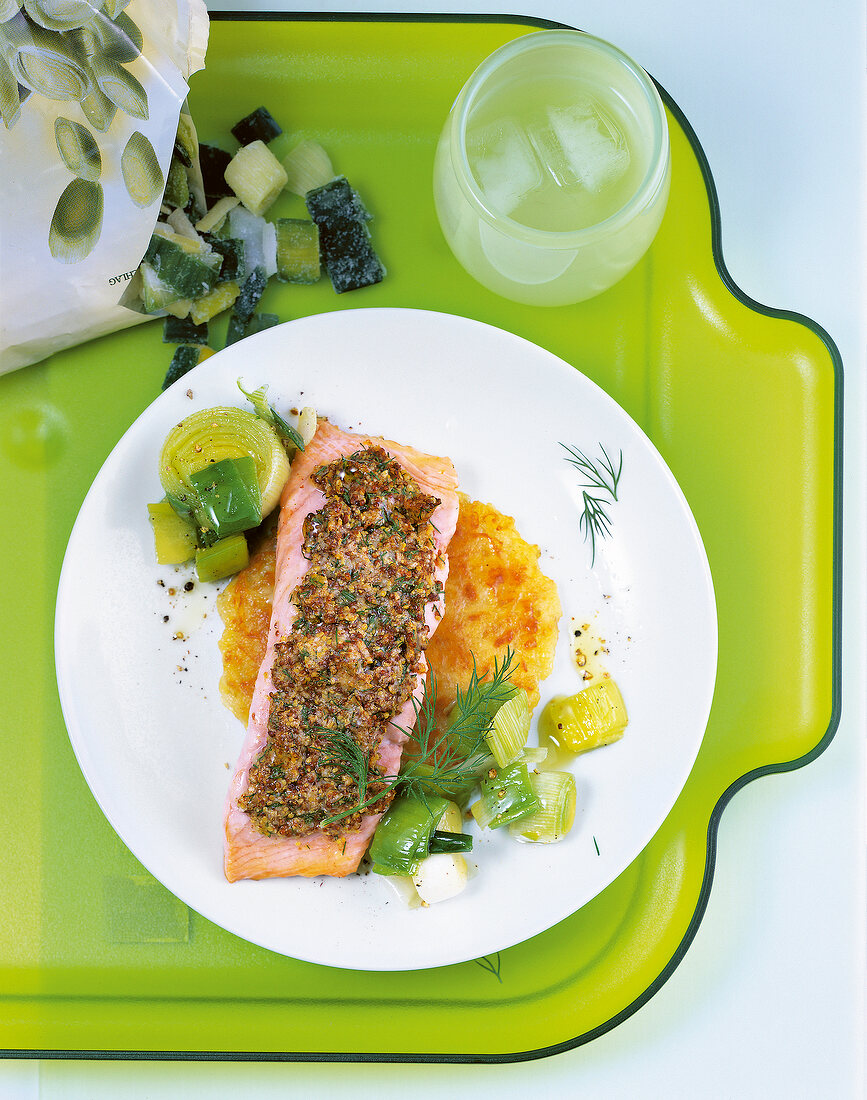 Plate of salmon fillet with mustard crust, leek and dill on green tray