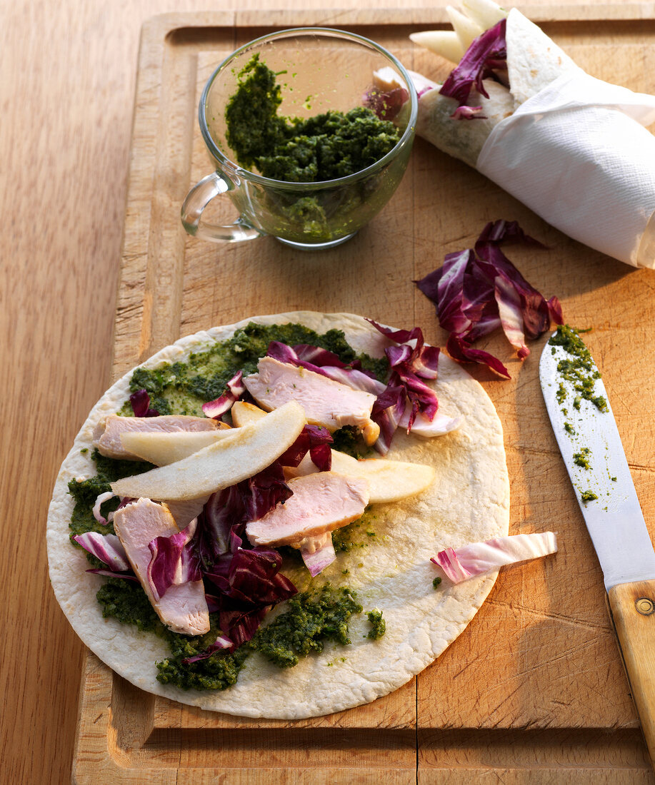 Chicken wraps with parsley and walnut pesto on wooden board
