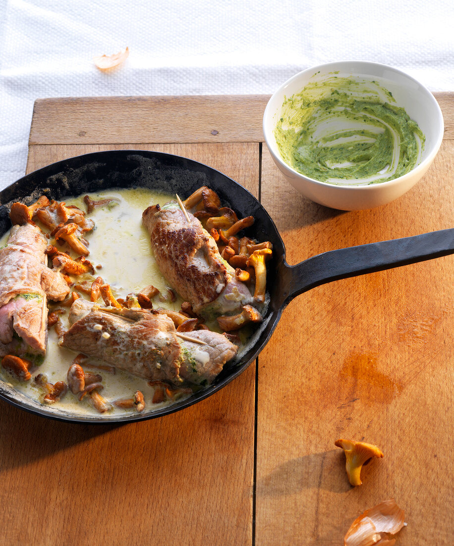 Bowl of thyme pesto and veal rolls with chanterelles in pan