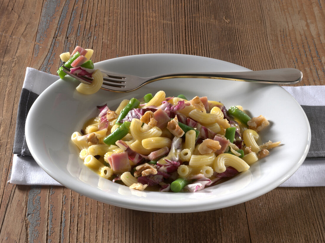 Ham, green beans and walnuts in dish on wooden table