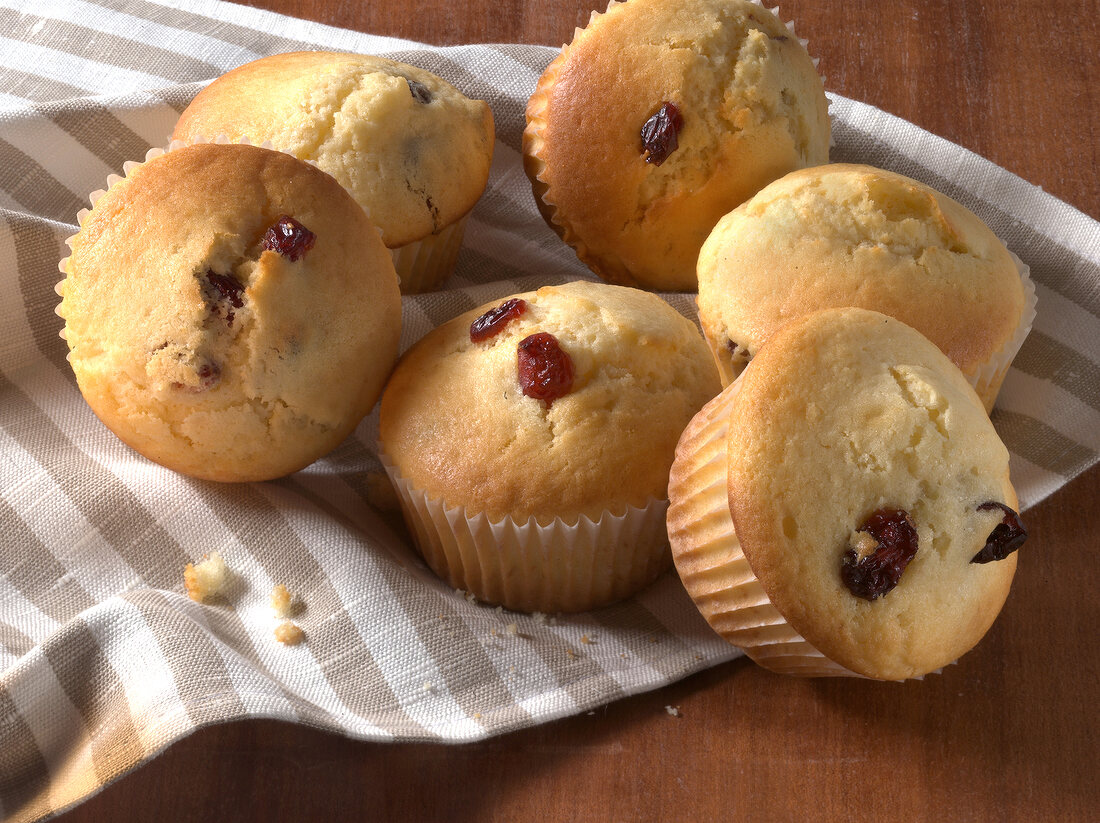 Six cranberry muffins on striped table cloth